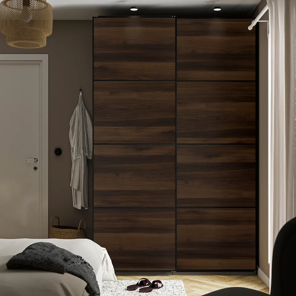 Modern bedroom with large wooden PAX wardrobe. Sliding doors save space, tall and wide, matching bed and small hanging light.