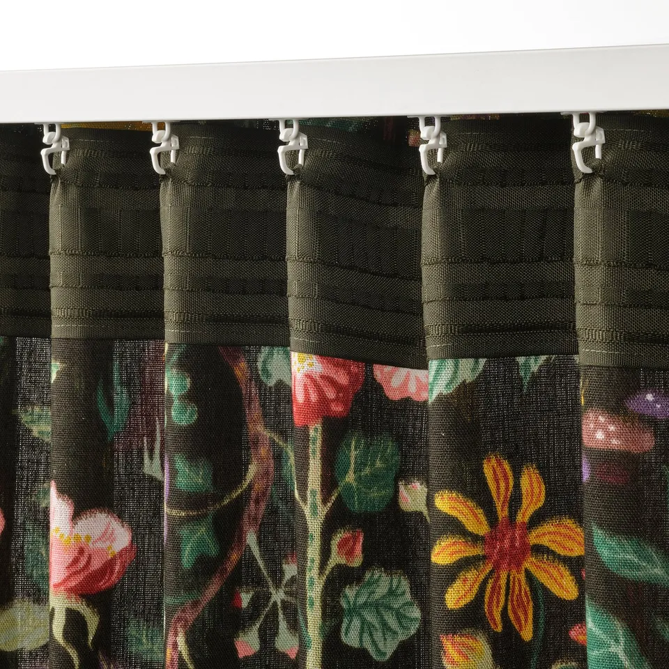 Black curtains with colourful floral prints hang from white hooks, allowing light control and privacy.