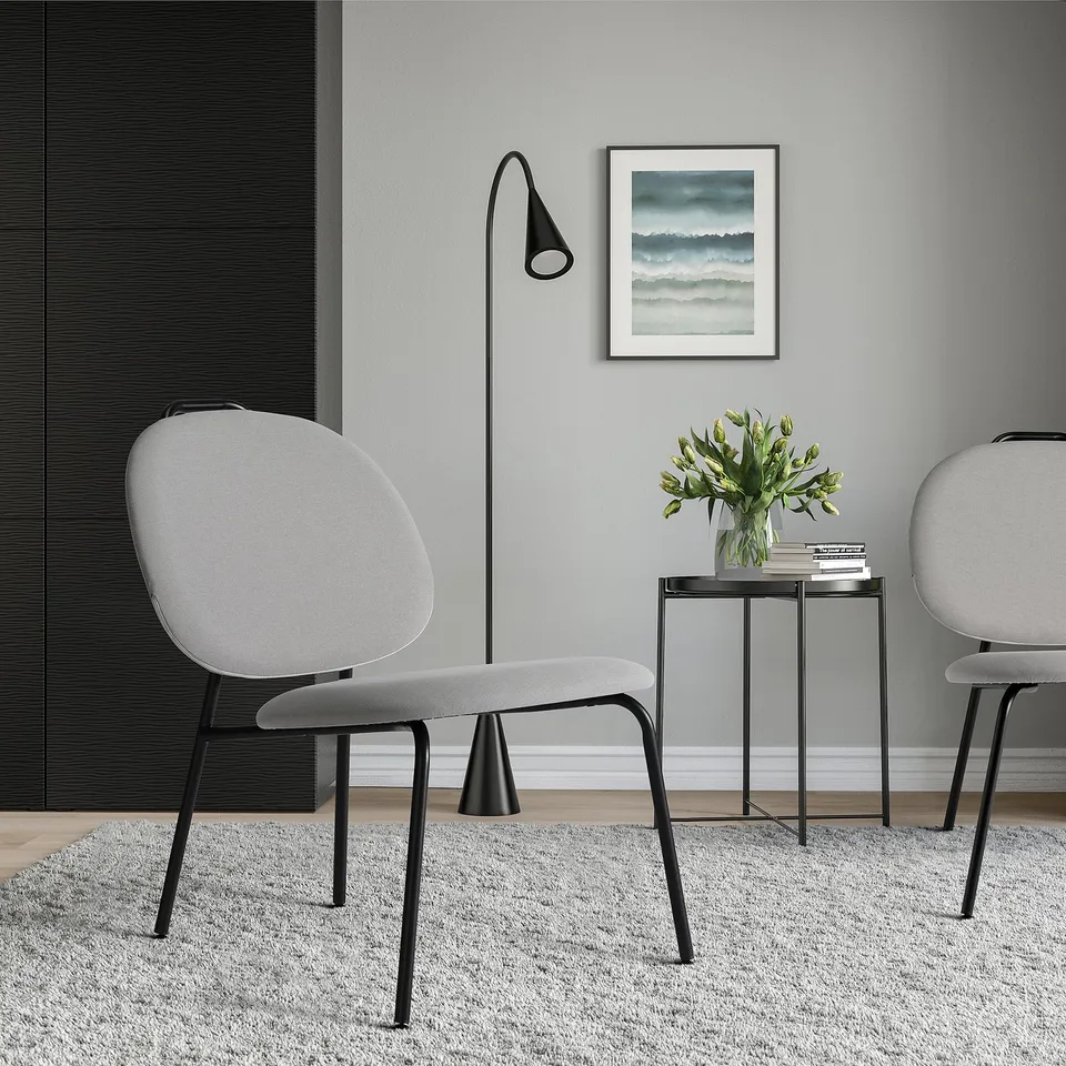 Modern living room with GÄVLE chair, lamp, rug, table with flowers, and print. Grey chair is comfy.