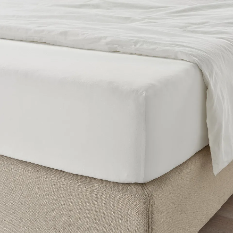 Bed with white ULLVIDE fitted sheet, featuring breathable, moisture-absorbent fabric, elastic edges, and high-density weave for durability.