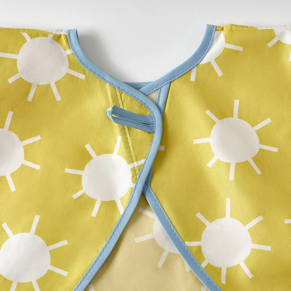 Childs bib with yellow sun print and blue trim. Soft, adjustable neck and hook-and-loop closure.