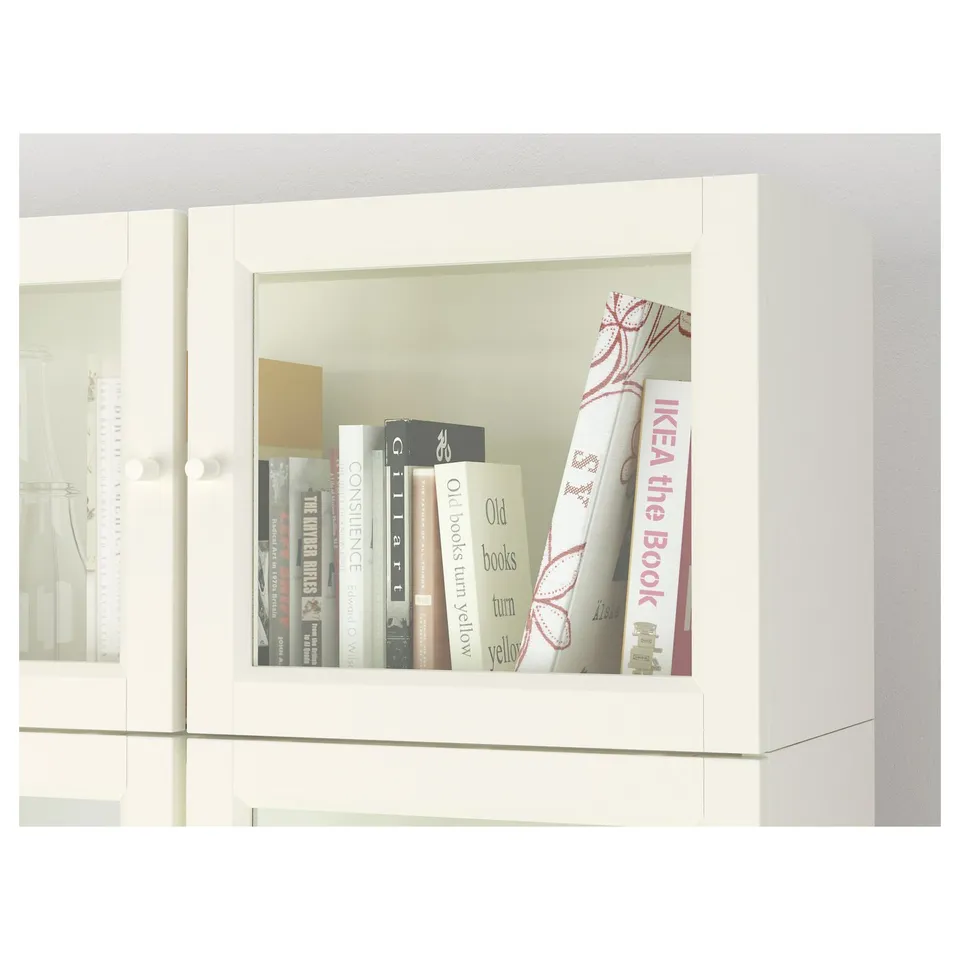 White bookcase with glass doors displaying books. Adjustable shelves inside.