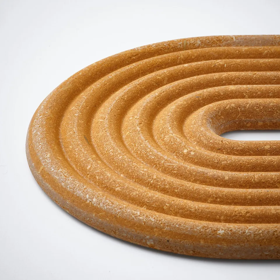 A round, textured coaster made of compressed, pigmented bamboo with a natural grain pattern, designed to protect surfaces from heat.