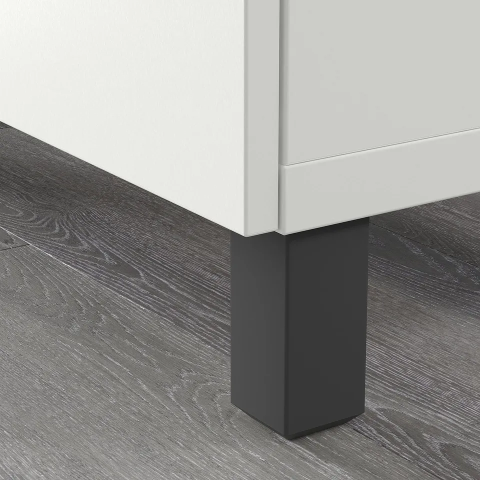 Dark grey STUBBARP legs elevate a white bestå unit, enhancing airflow and ease of cleaning. Adjustable feet ensure stability on uneven floors.