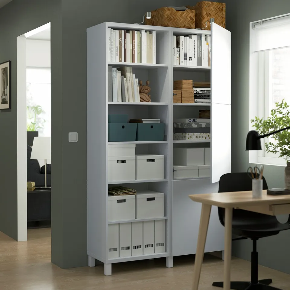 A modern storage unit with adjustable shelves, displaying books, boxes, and decor on one side, while the door hides other items.
