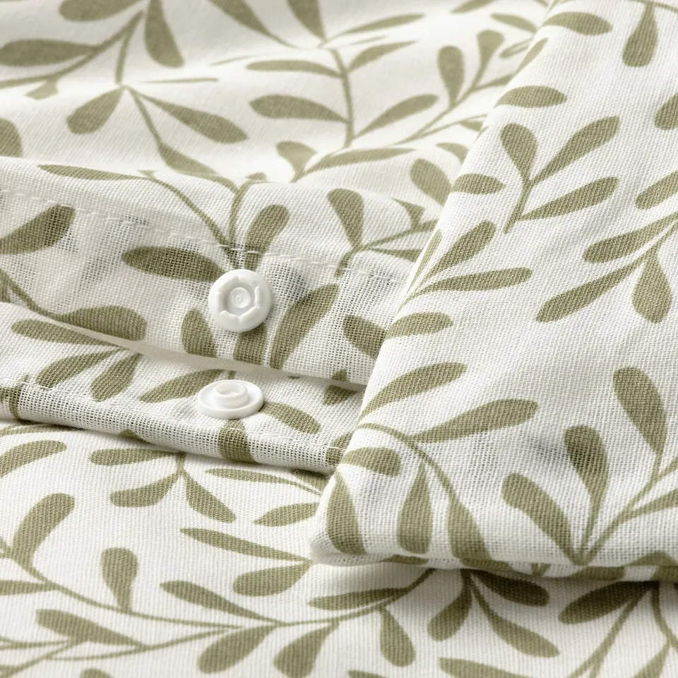 Close-up of a bedding set with green leaf patterns and plastic press-stud closure.