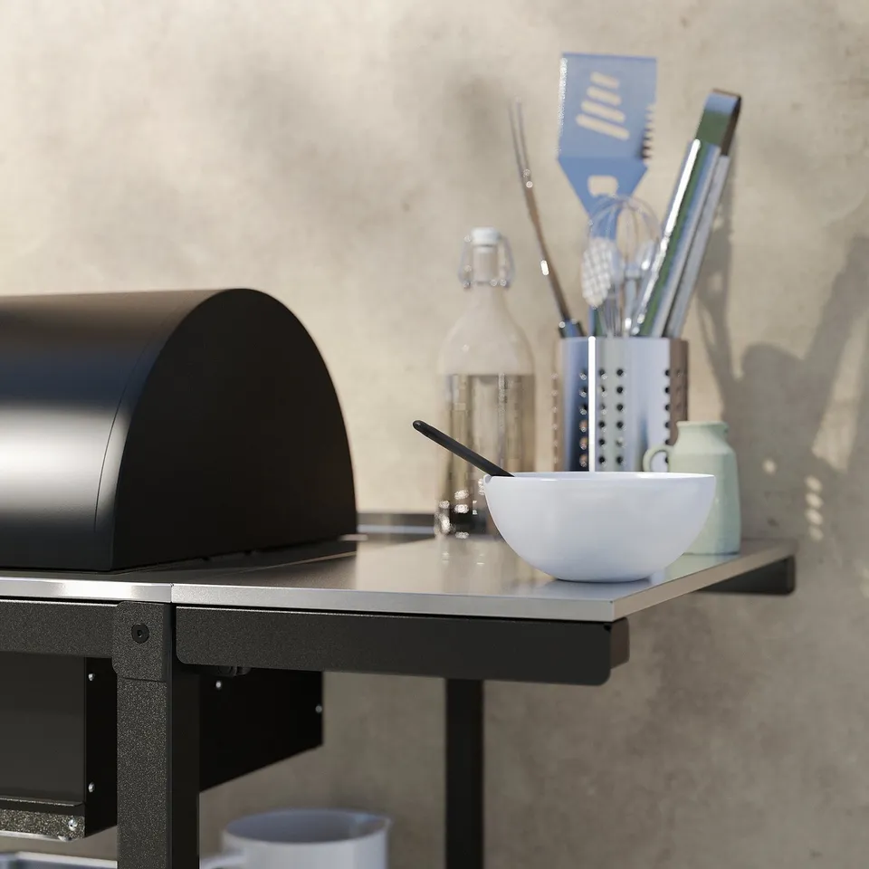 Modern black outdoor grill setup with tools & bowl on stainless shelf.