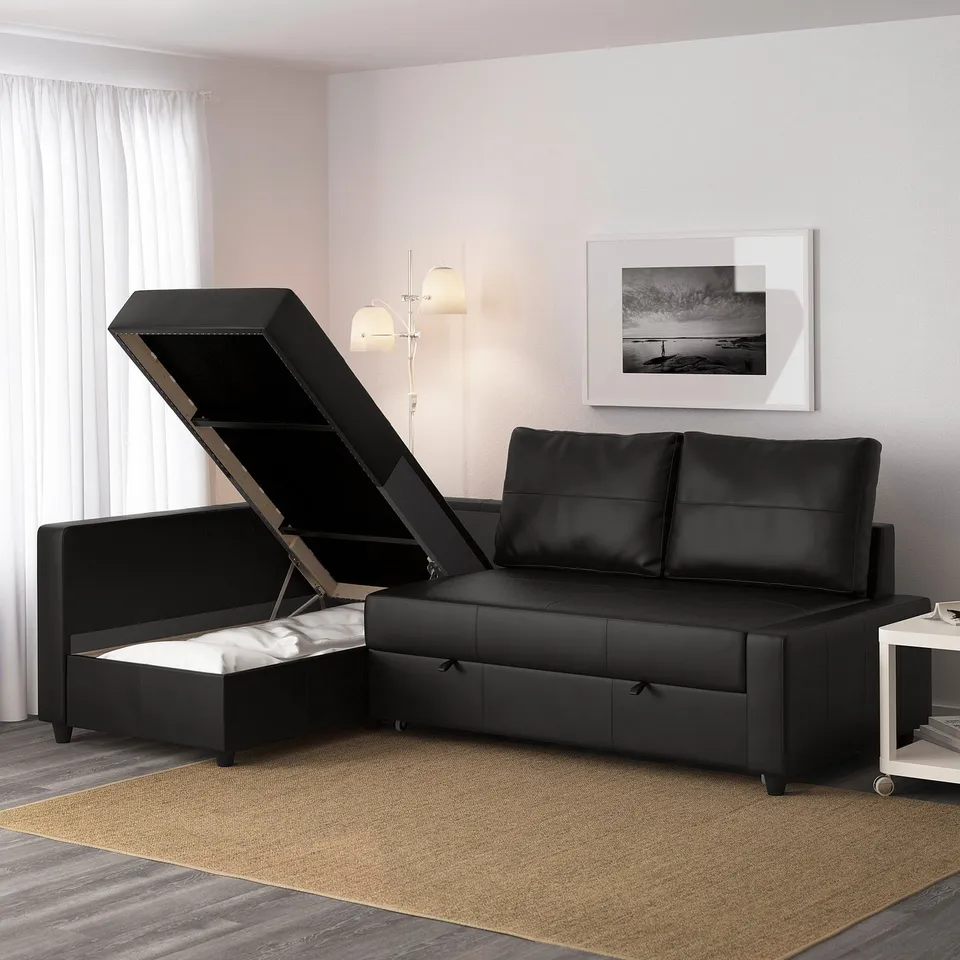 Black convertible sofa with open storage compartment, showcasing integrated bedding storage.