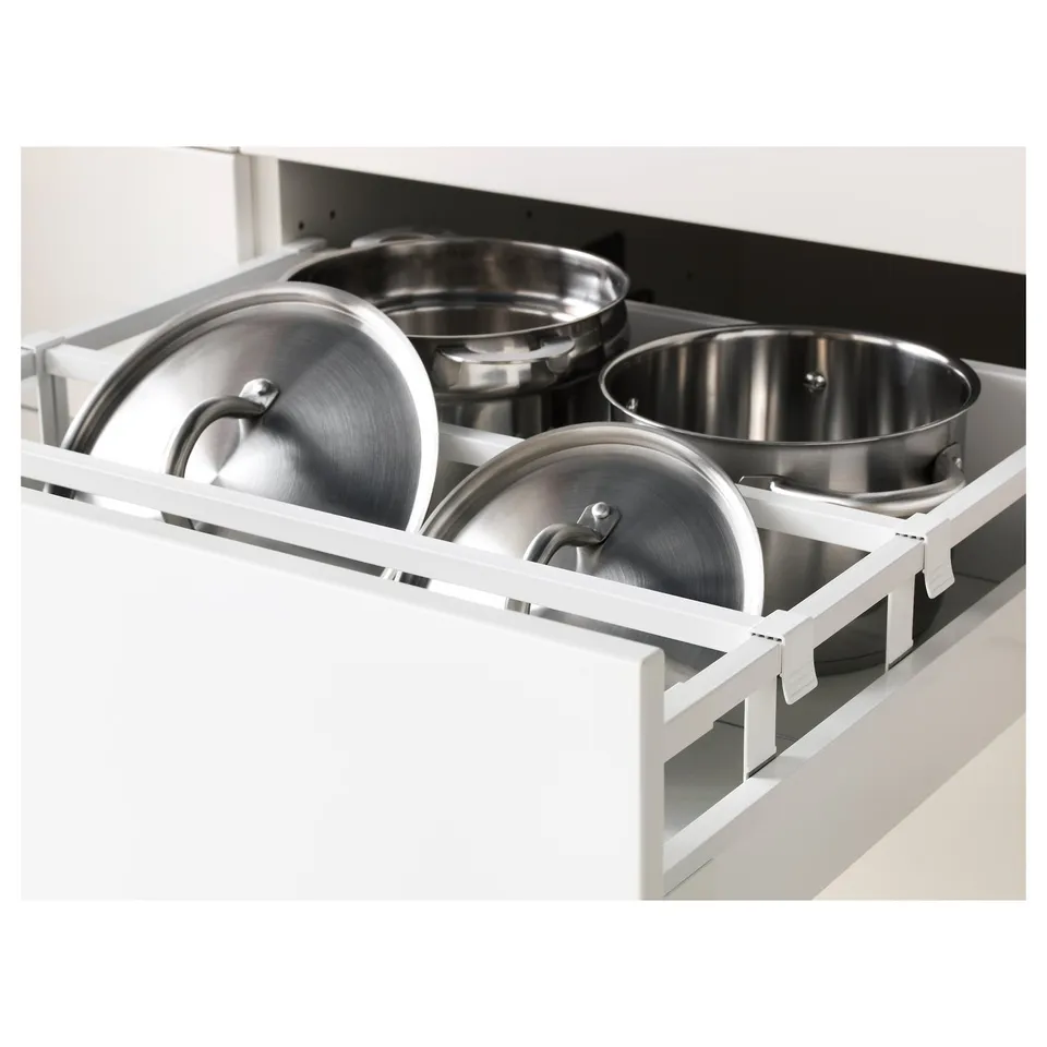 Metal pots with lids in white kitchen drawer, organised and accessible.