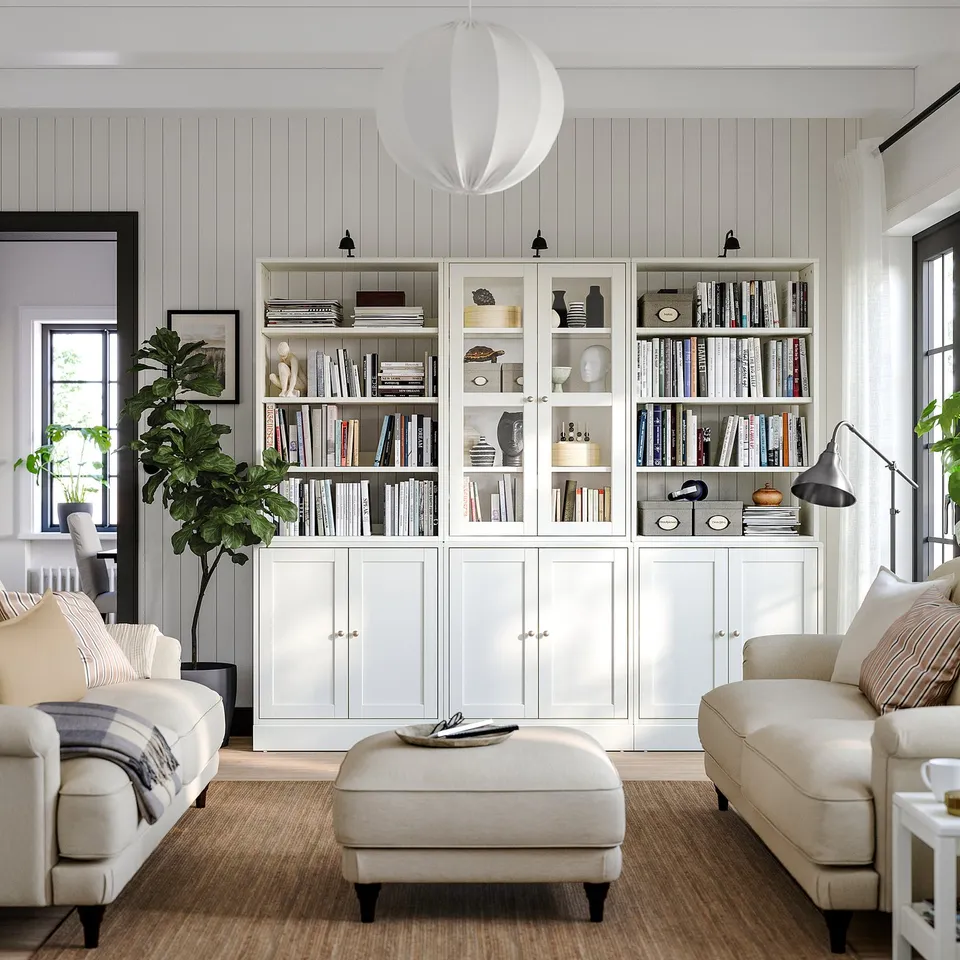Bright, modern living room HAVSTA white pine cabinet with glass and solid doors, cream sofas, and a large plant.