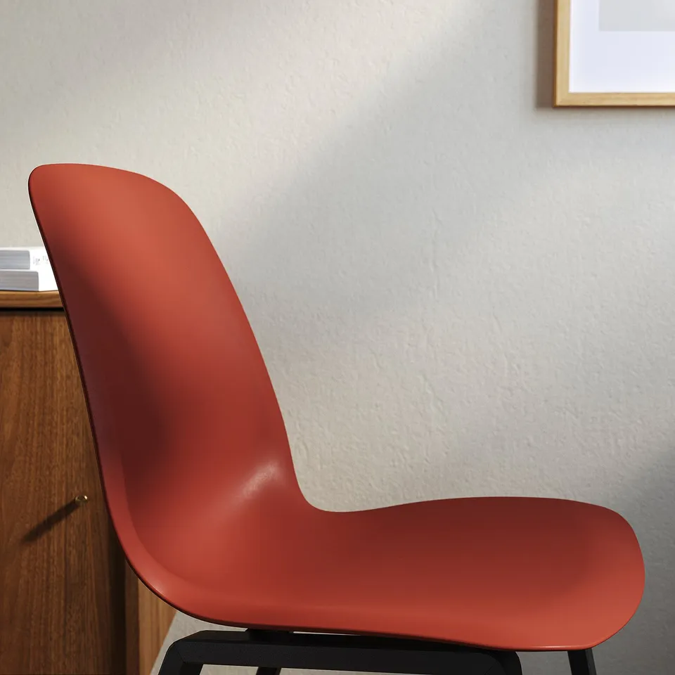 Bright red chair with sleek, ergonomic design against a plain wall, showcasing modern and comfortable office seating.