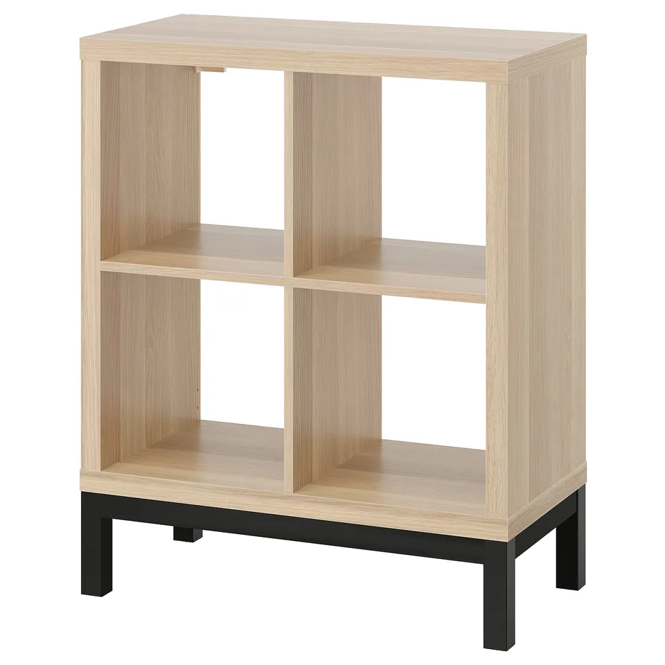 Light wood KALLAX shelving unit, black legs, four open cubes, minimalist design.