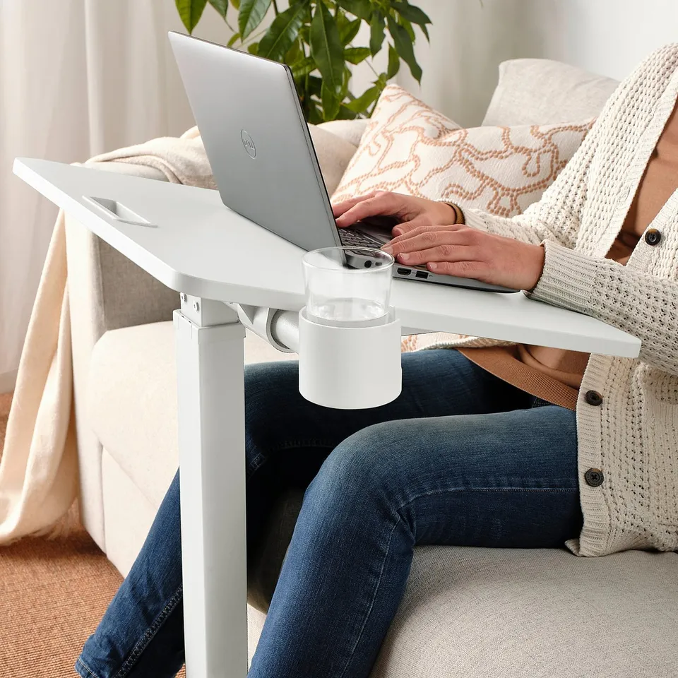 Person sitting, typing on laptop using a height-adjustable MITTZON table with a cup holder.