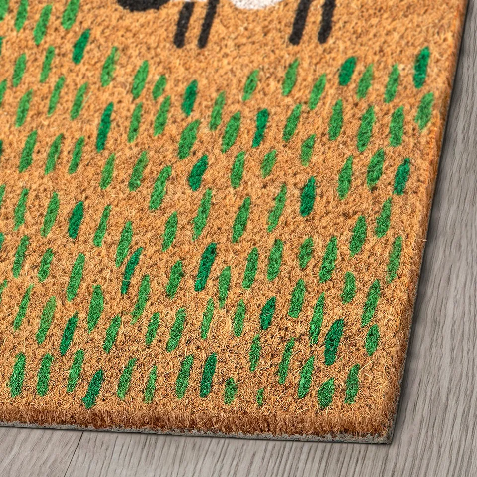 Close-up of LÖGE door mat. Textured coir surface with green leaf patterns. Natural and durable material.