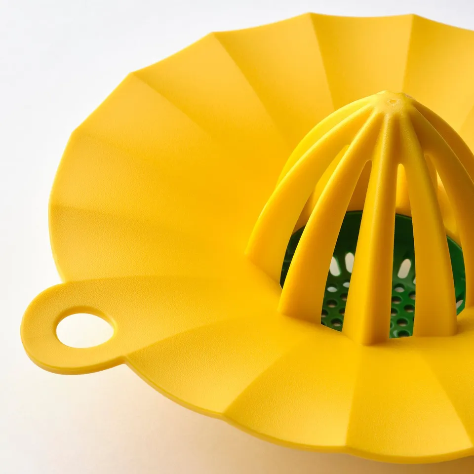 Bright yellow citrus squeezer with green interior holes, smooth handle, and textured surface.