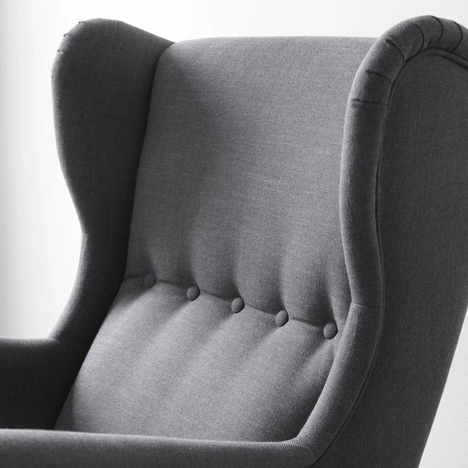 Close-up of a dark grey, plush wingback chair. Soft, high-quality upholstery with detailed stitching.