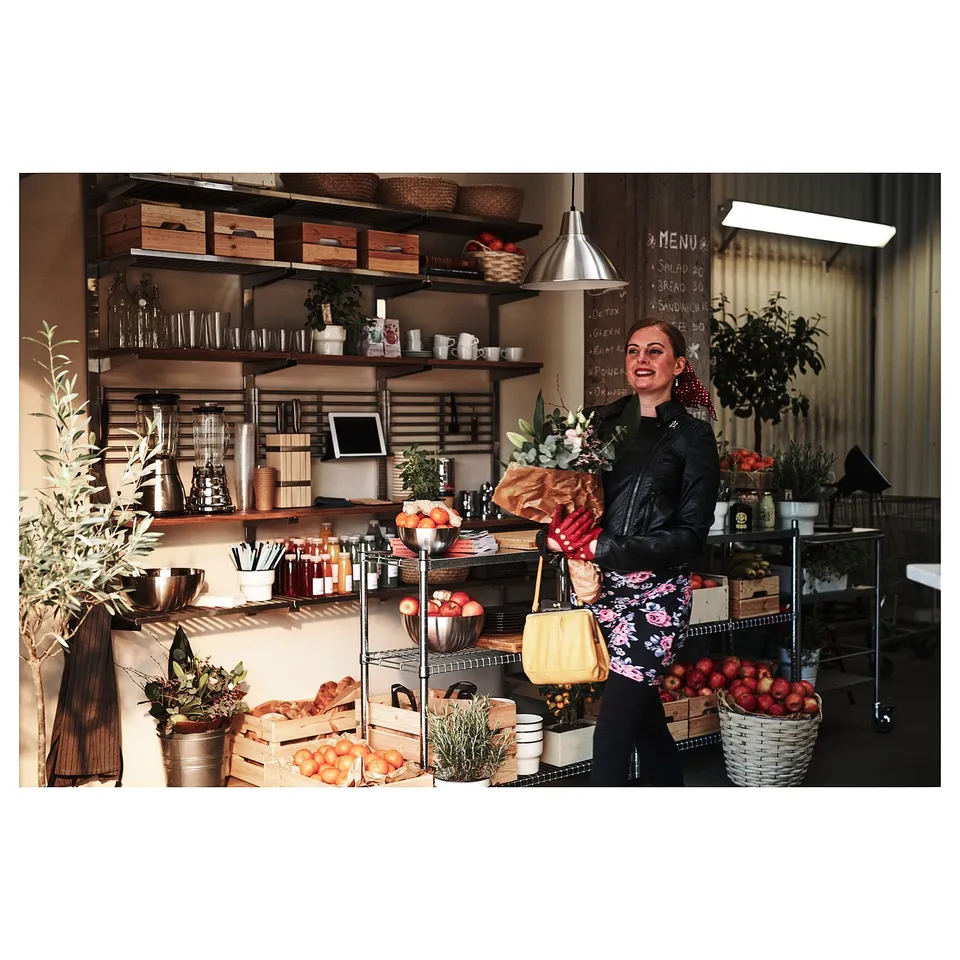 Person in kitchen with KUNGSFORS shelves, flowers, and bag.