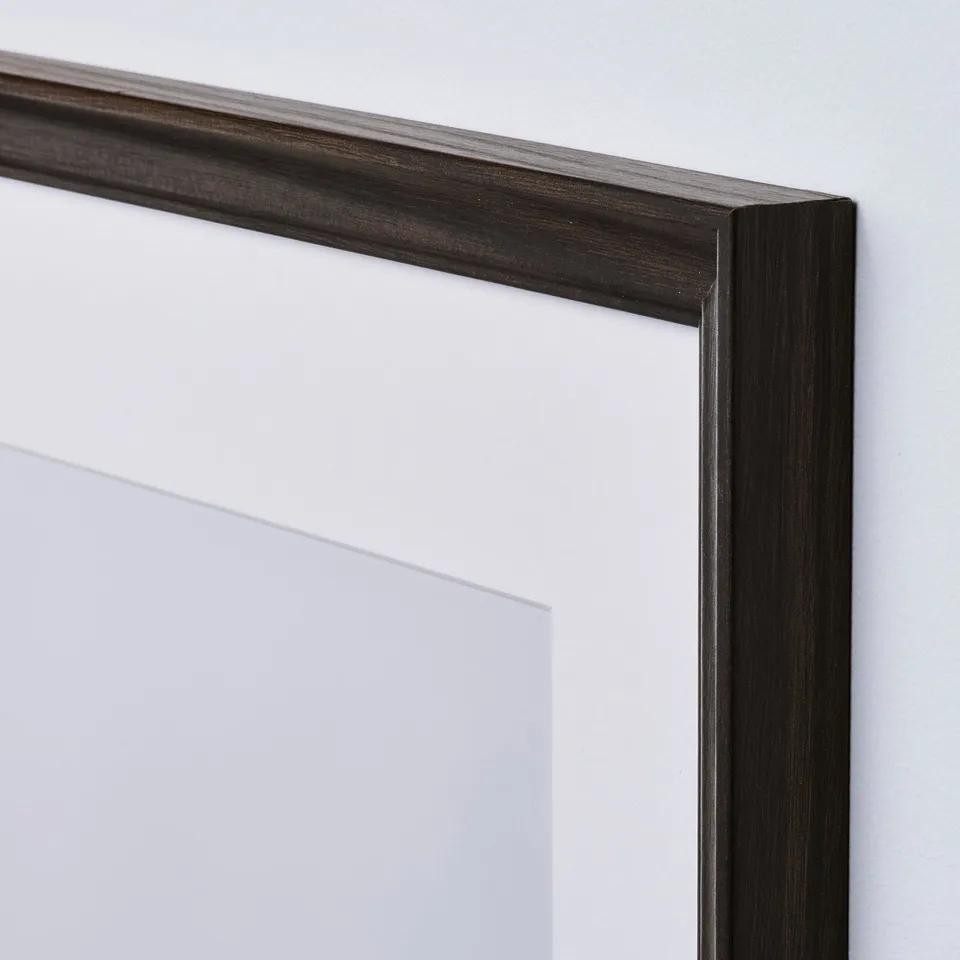 Close-up of dark brown picture frame on white wall.