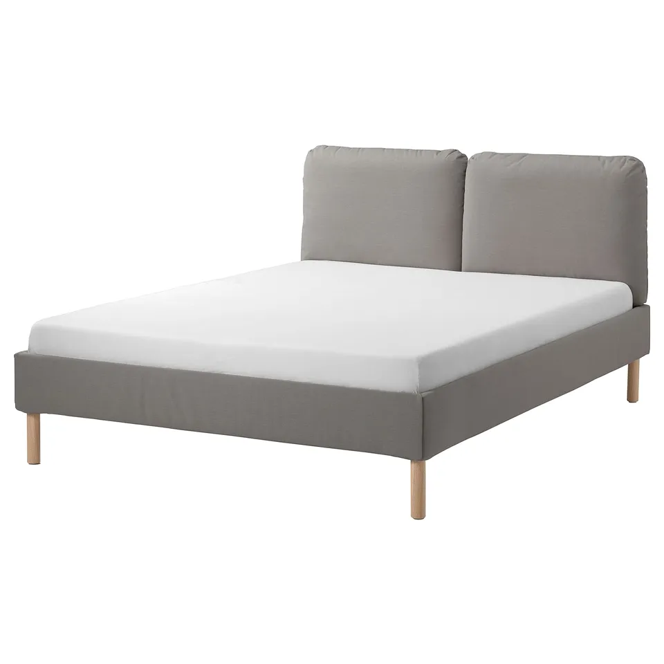 A modern SAGESUND bed in grey fabric with wooden legs and a slightly sloped headboard featuring two soft pillows.