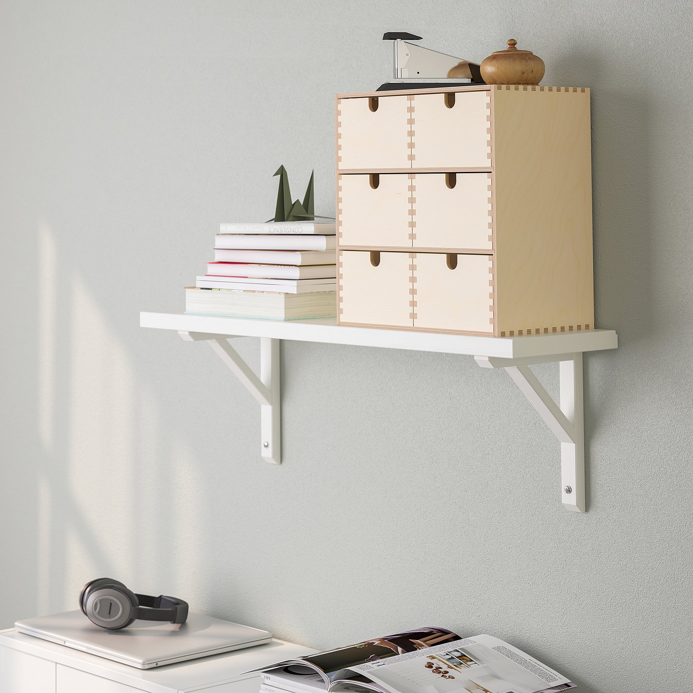 A wall-mounted shelf with drawers and brackets holding books and decor.