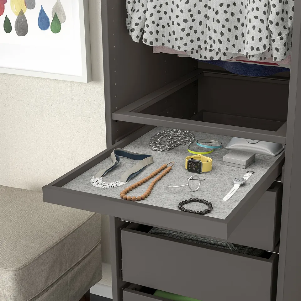 Open grey KOMPLEMENT drawer with jewellery: necklaces, watches, and accessories on felt tray.