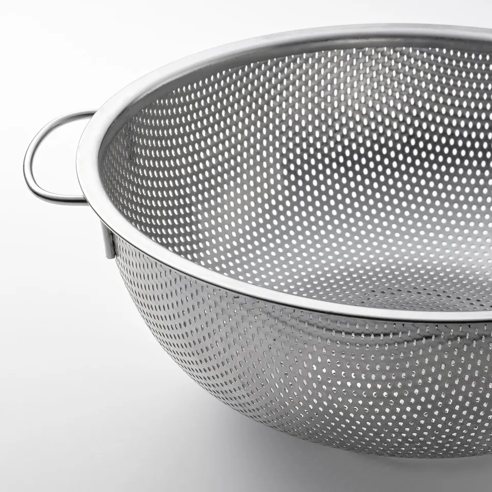 Stainless steel colander with large handle and perforated bottom.