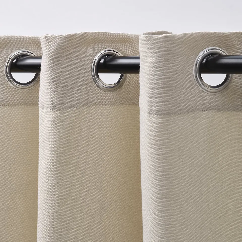 Beige curtains with eyelets hang neatly, blocking light while adding serene style.
