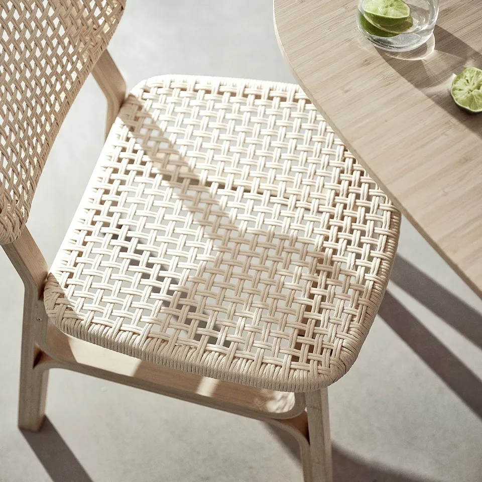 Wicker chair with voxlov design, natural colour, bamboo & paper seat, near light wooden table with drink.
