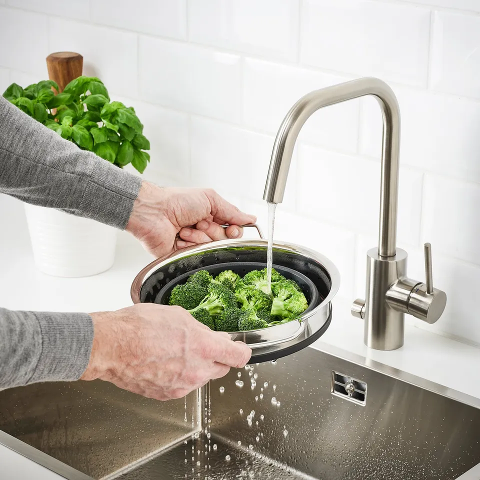 Person washes broccoli in sink using KLOCKREN silicone colander.