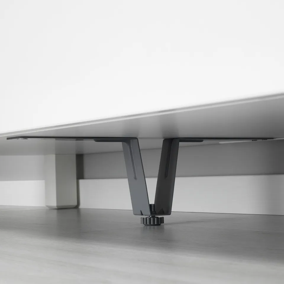 Black metal leg supports a white furniture panel, providing stability. Part of BESTÅ series, ensuring heavy items are securely held.