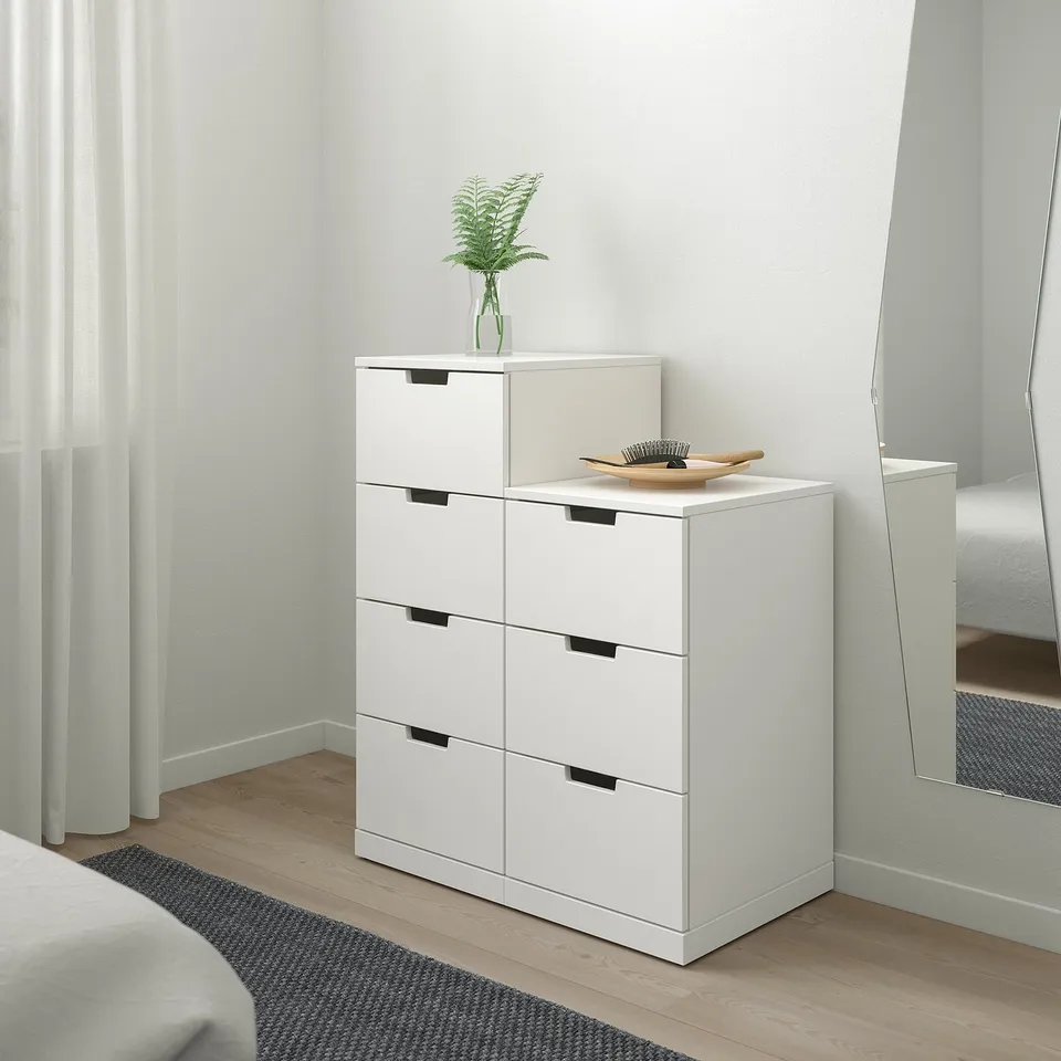 NORDLI chest with 6 drawers, plant, mirror, and rug in bedroom