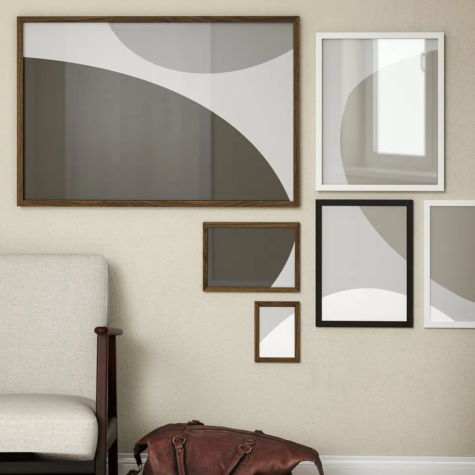 Modern wall art display: RÖDALM frames in brown, holding abstract prints. Chair & bag below, emphasising size.