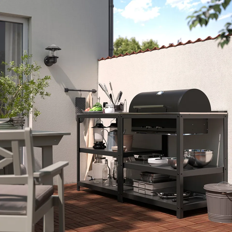 Charcoal grill on wooden patio, stainless steel accents, outdoor furniture.