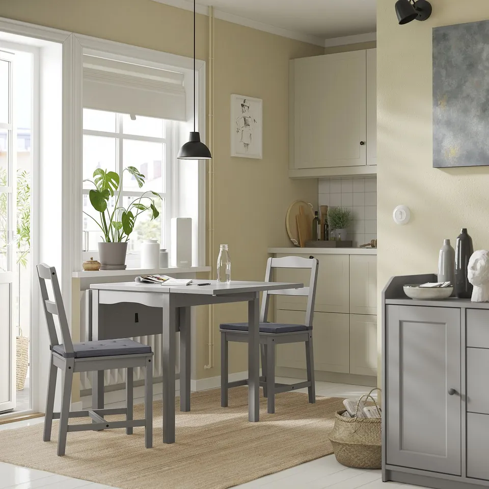 Cosy kitchen nook with grey JUSTINA chairs, whitewashed table, and hanging plant near large window.
