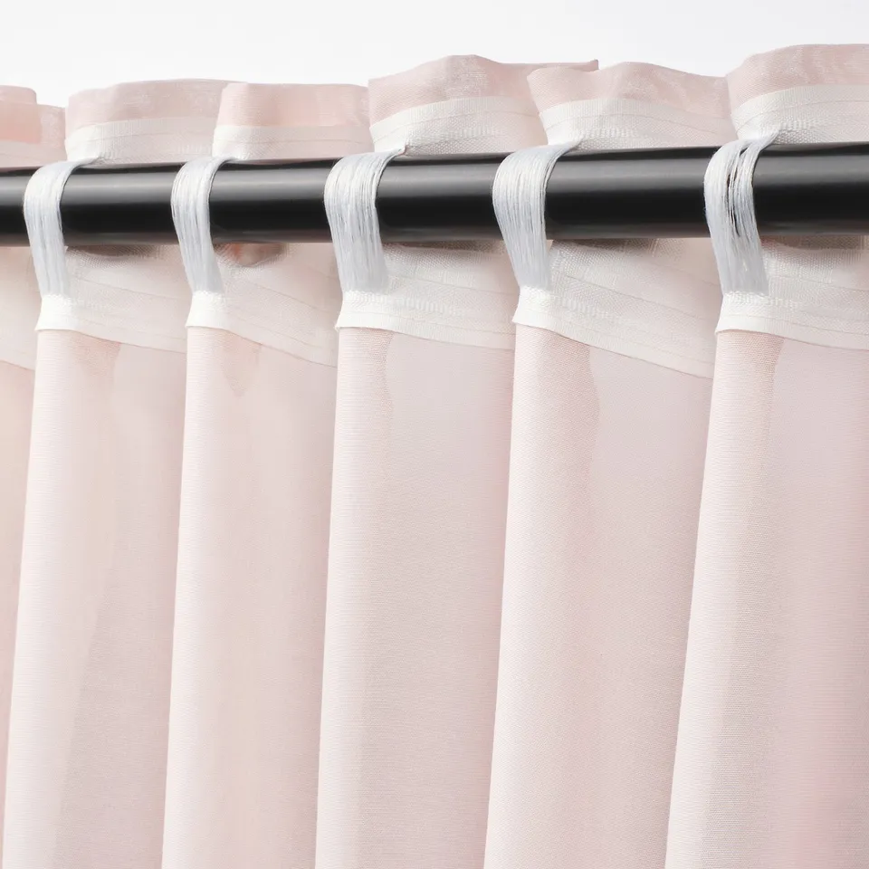 Pink sheer curtains hanging with white tabs and rod, diffusing light for privacy.