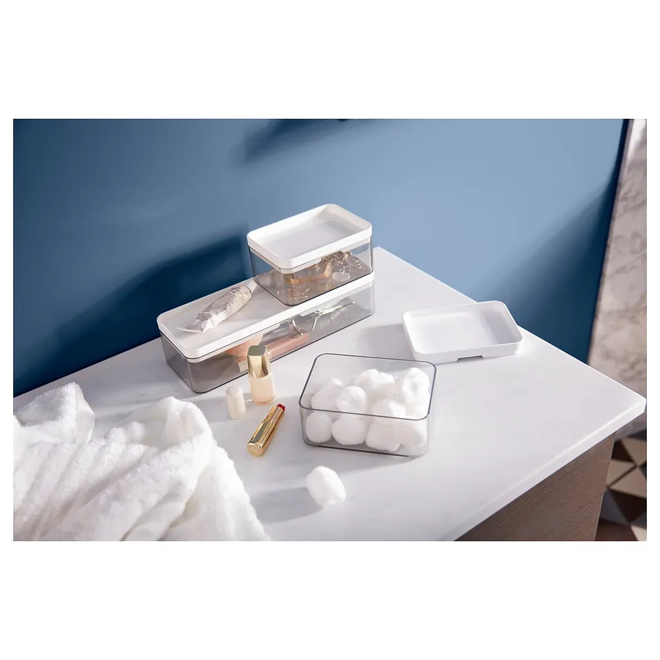 BROGRUND clear plastic storage set, containing makeup and cotton swabs, placed on a white countertop against a blue wall.