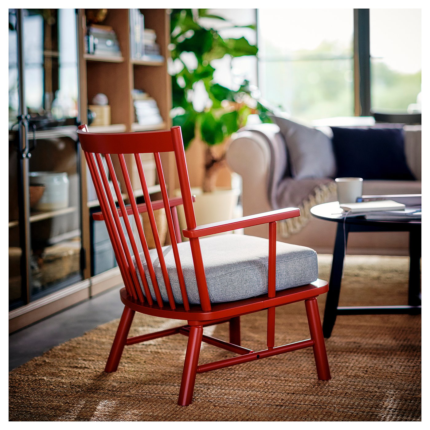Red PERSBOL chair, wooden with spindle design, grey cushioned seat in cosy living room, near window and couch.