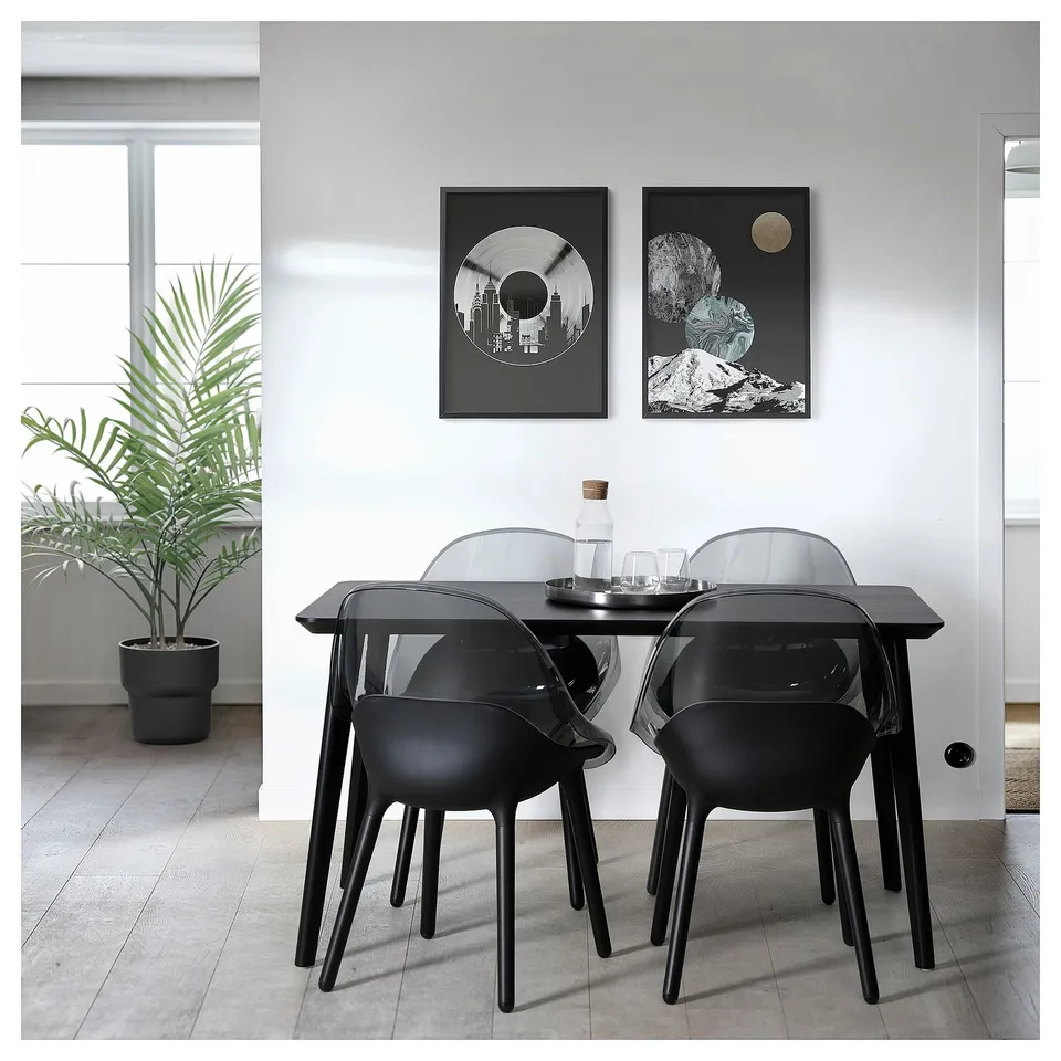 Modern dining area with black BALTSAR chairs & table, art on wall, plant.