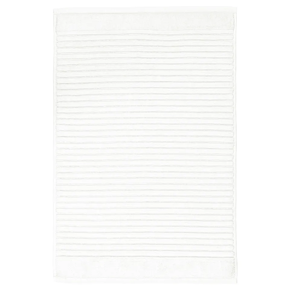 A white, rectangular ALSTERN cotton terry bath mat. Its design a textured surface for foot massage and quick drying.