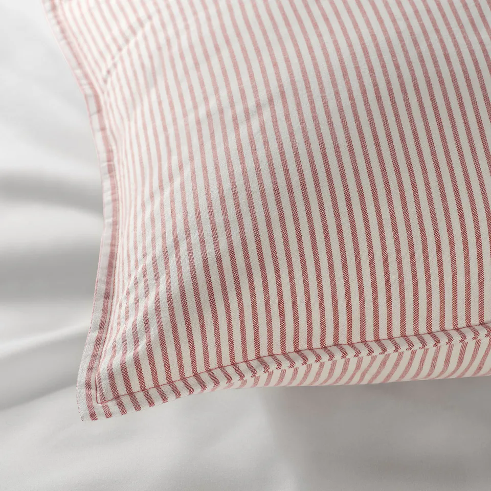 Striped red and white pillow, showcasing soft, high-quality cotton texture. Detailed stitching visible, emphasising craftsmanship.
