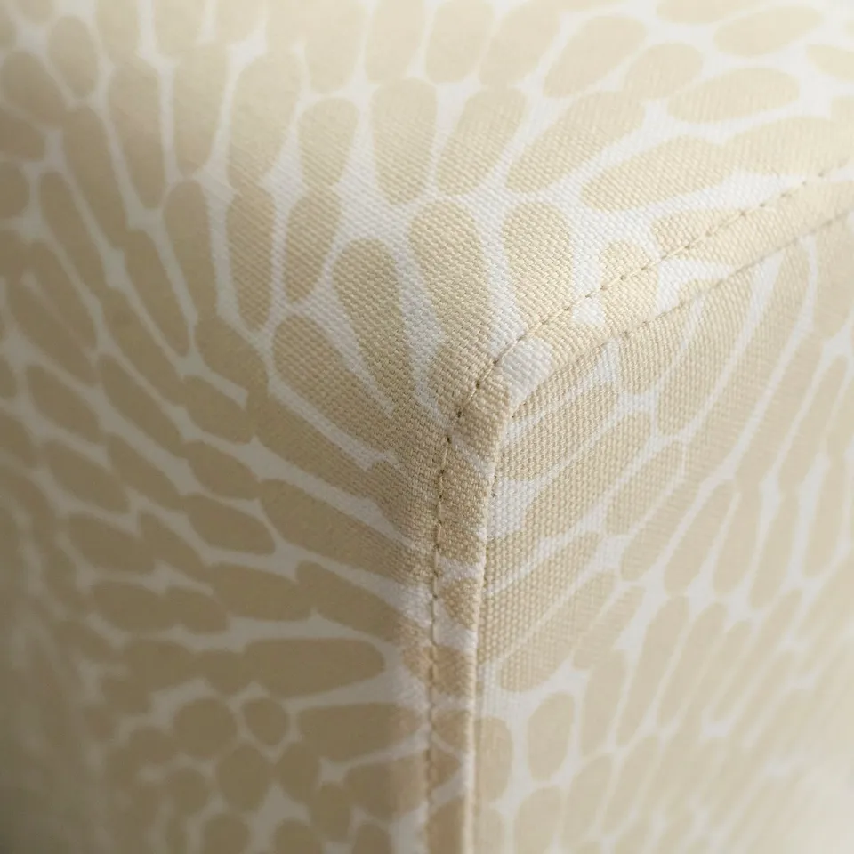 Close-up of plush, upholstered chair corner with intricate, geometric pattern. High-quality stitching ensures durability.