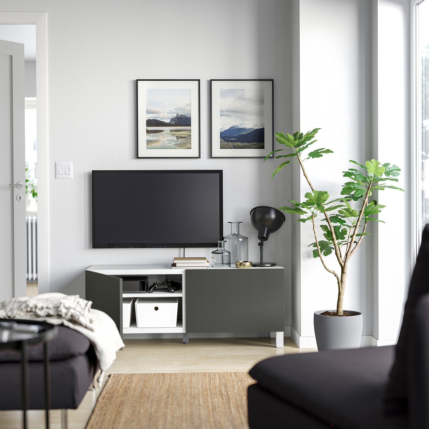 Modern living room with grey BESTÅ tv unit, flat screen tv, decorative plant, and framed landscape art.