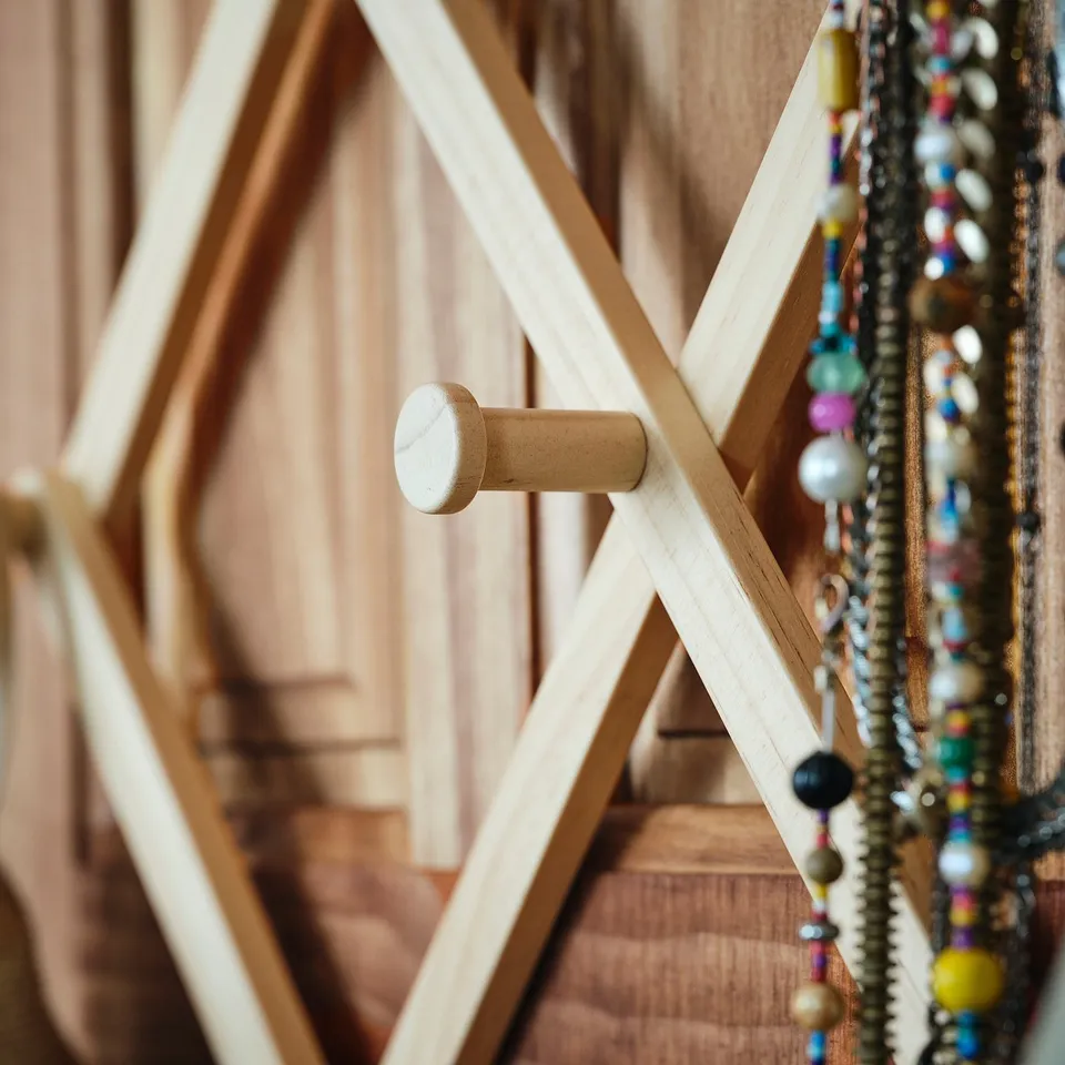 Wooden door hanger with multiple hooks, displaying beaded necklaces. Crafted with natural wood finish and functional design.