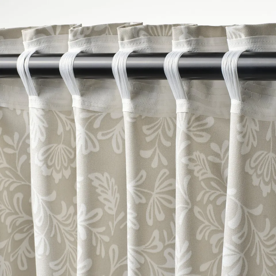 Curtain closeup: beyong rod, hooks, hooks loops hold fabric; floral-patterned.