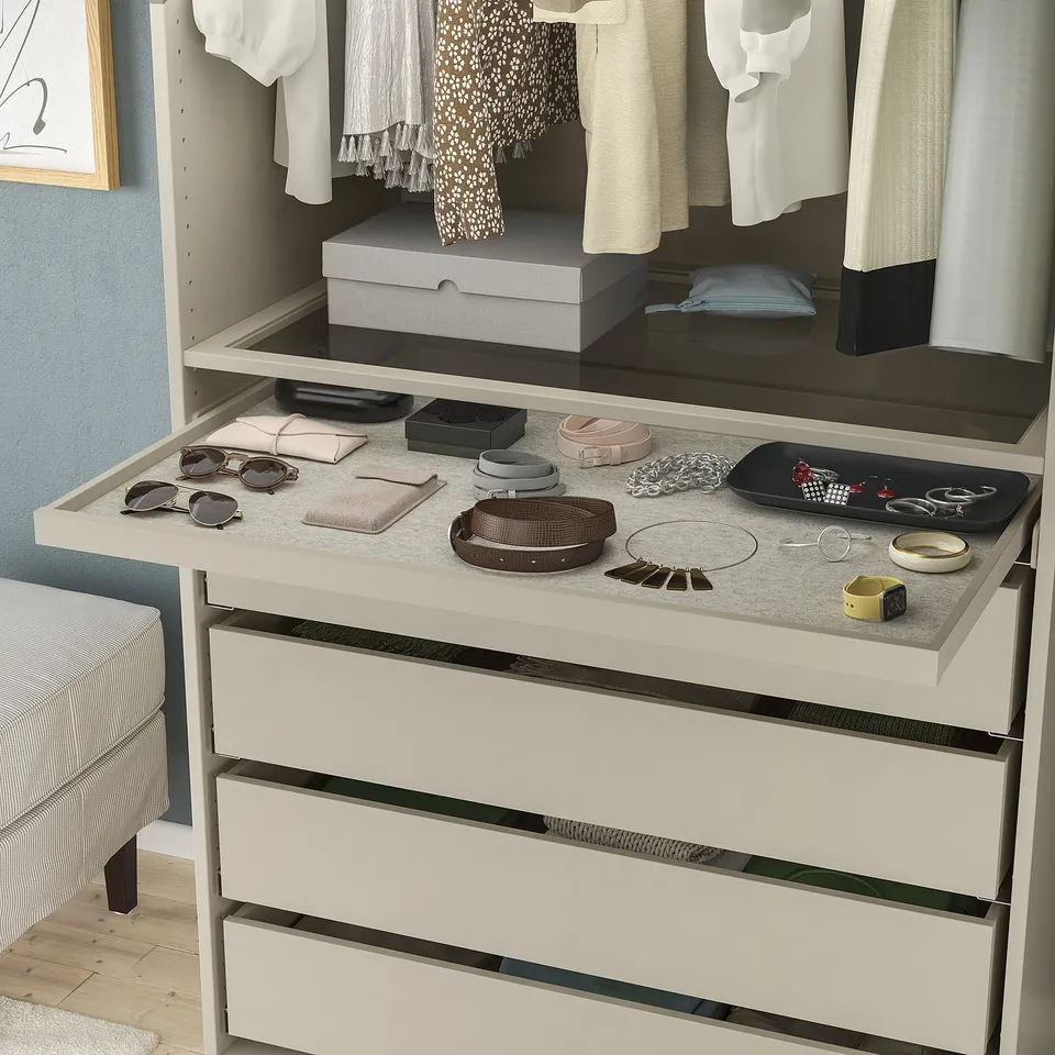 Organised dresser with accessories tray, jewellery, sunglasses, and belts neatly arranged. Wardrobe with hanging clothes above.