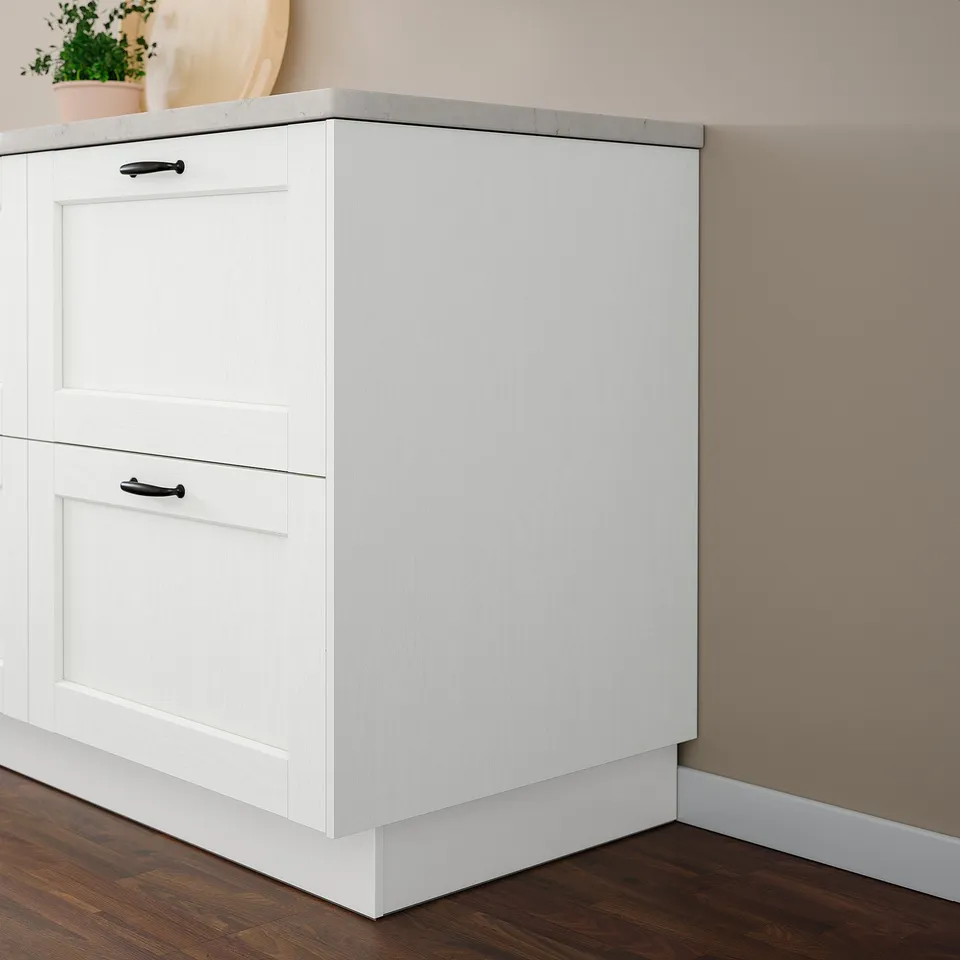White ENKÖPING cabinet with dark handles, positioned against a peach wall. Smaller than nearby wall.