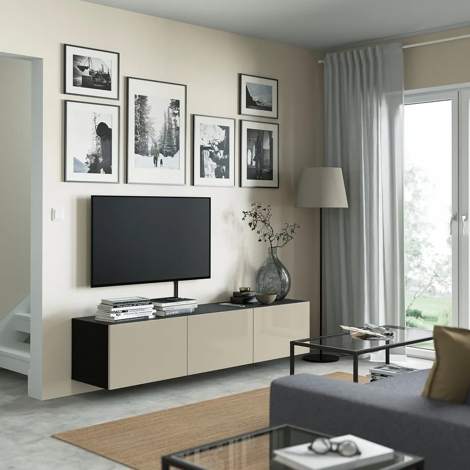 Modern living room with BESTÅ tv bench, flat screen tv, grey lamp, glass coffee table, grey sofa, brown rug, window with curtains.