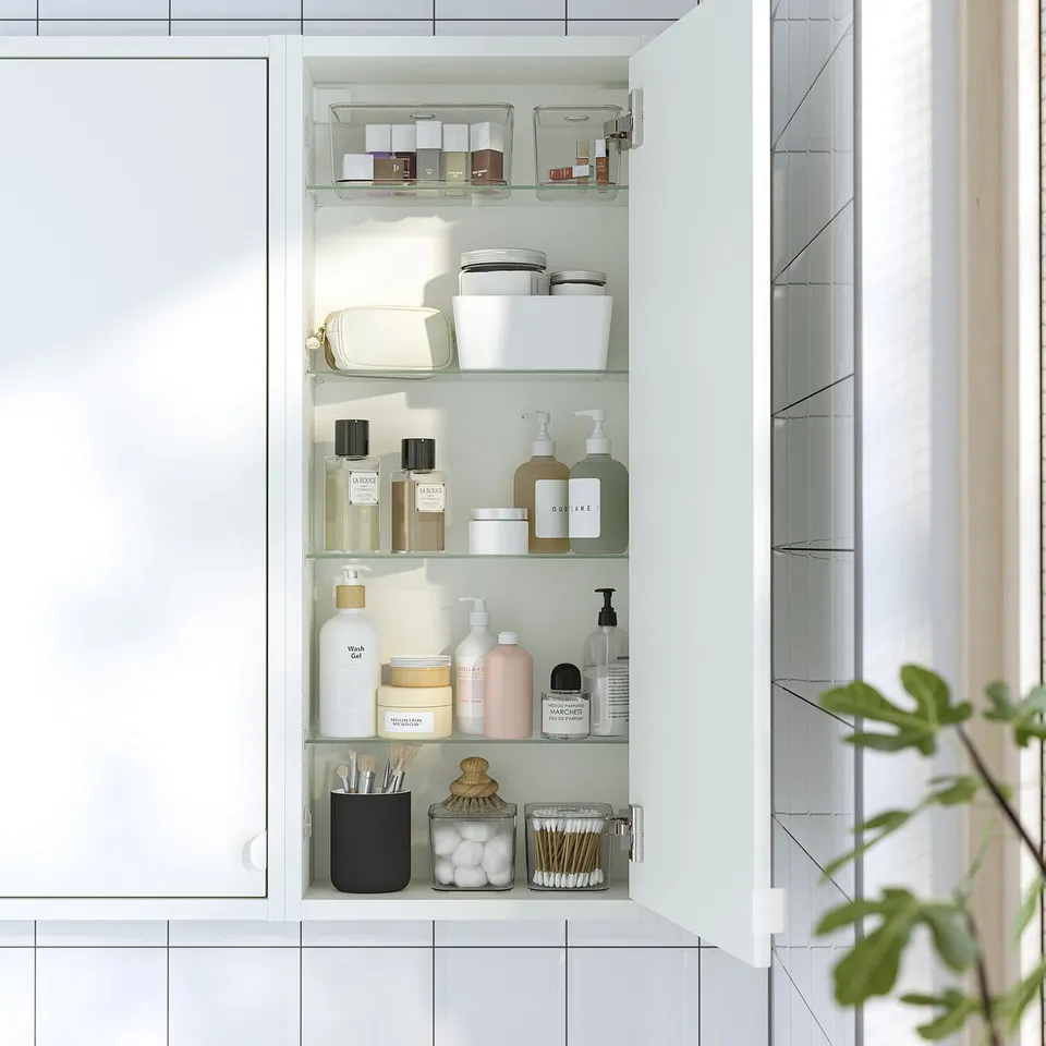 Organised bathroom cabinet with clear containers on glass shelves.