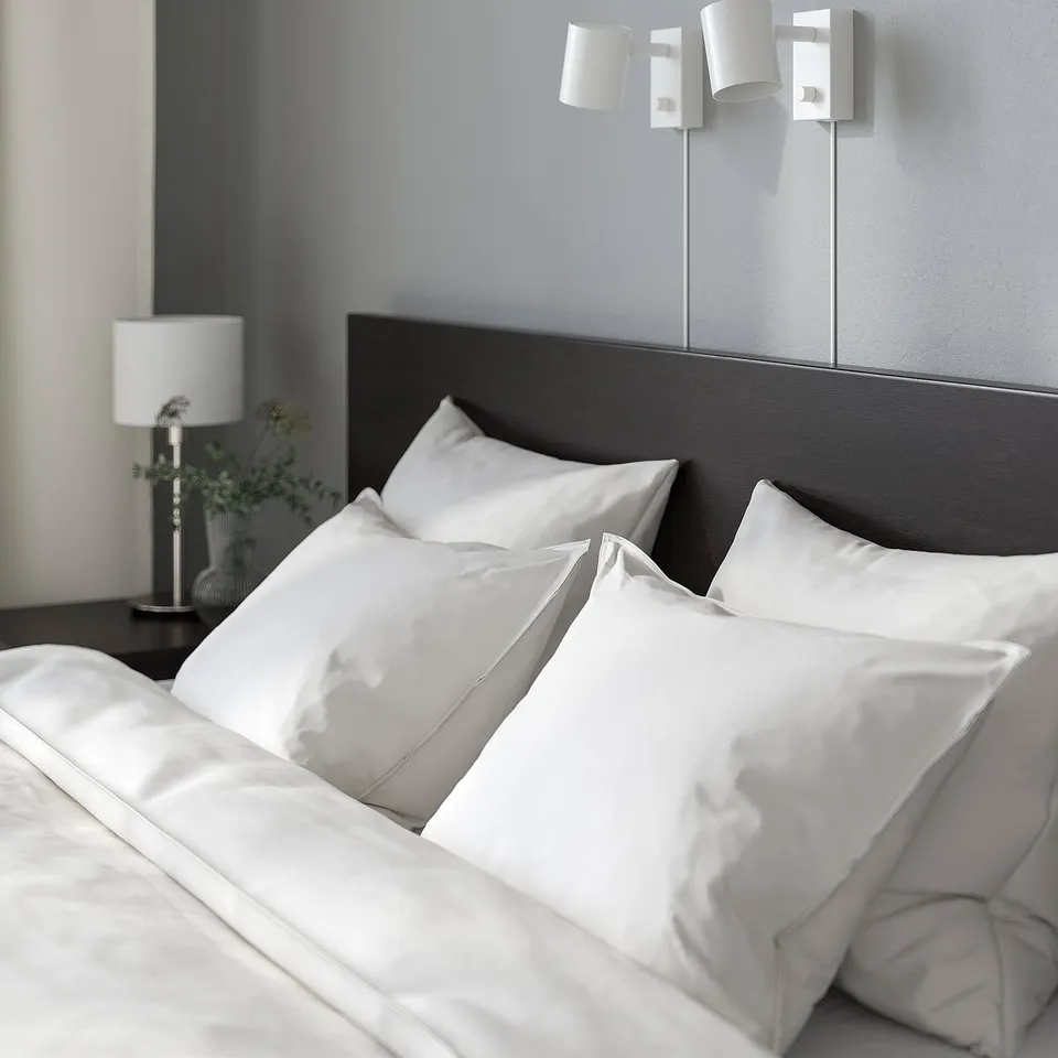 Modern bedroom with MALM bed, white silk bedding, dark headboard, and wall-mounted lamps.
