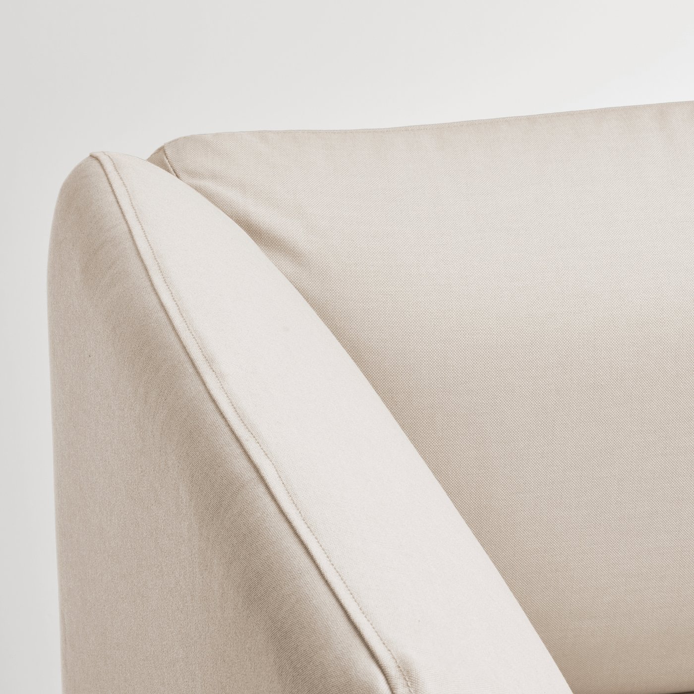 Sofa corner detail: smooth, beige fabric with neat stitching, showcasing high-quality upholstery.